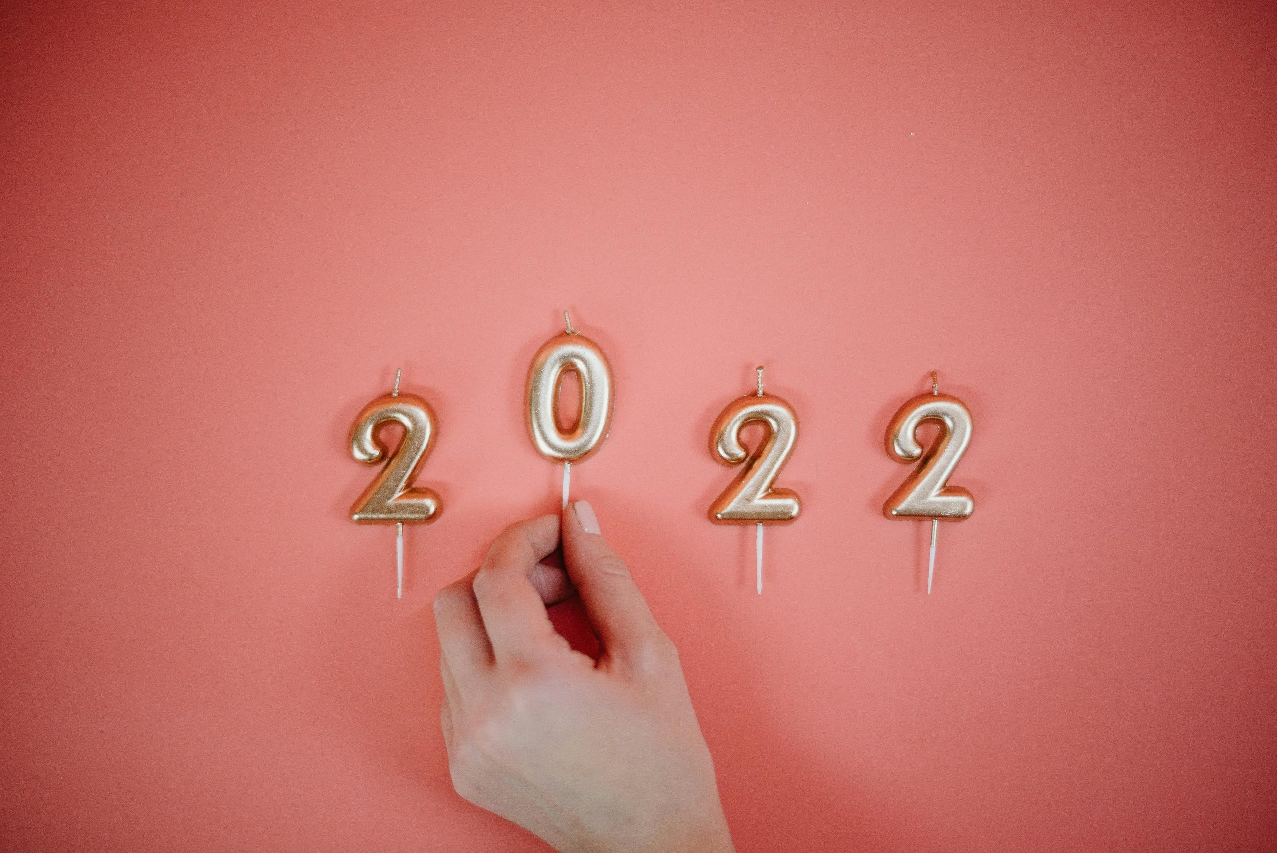 Celebrate the New Year 2022 with golden number candles on a pink backdrop.