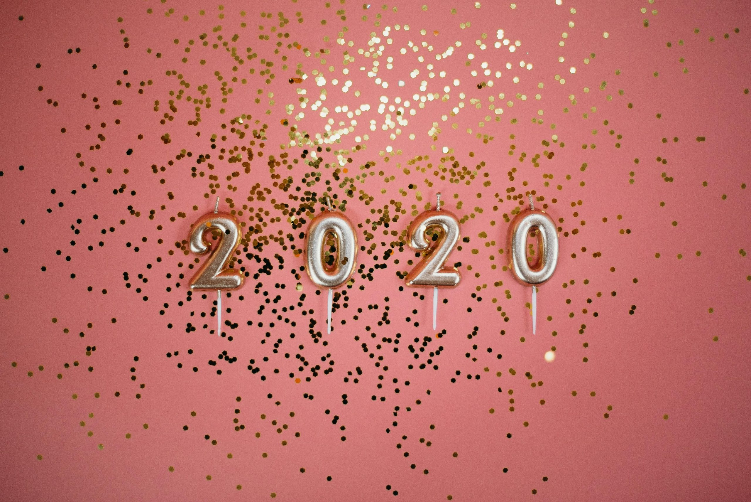 A festive pink background with 2020 candles and gold glitter, perfect for party themes.